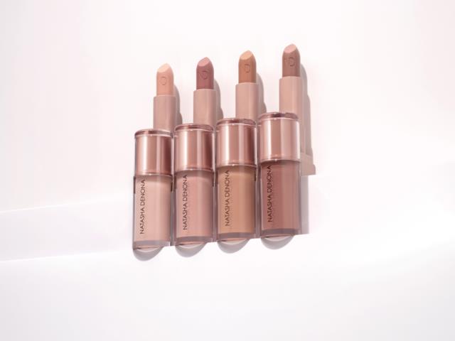 Fyra beige och rosa läppstift i genomskinliga hylsor, placerade i rad på en vit bakgrund.