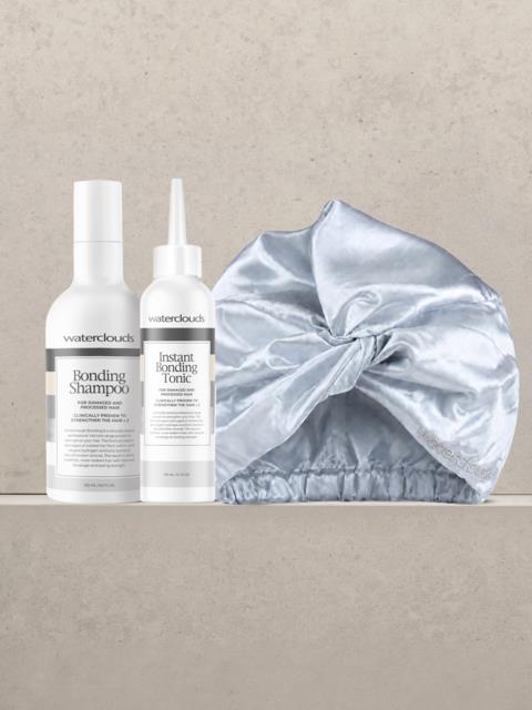 Två hårvårdsprodukter från Waterclouds, Bonding Shampoo och Instant Bonding Tonic, med en silvrig satin duschmössa bredvid.