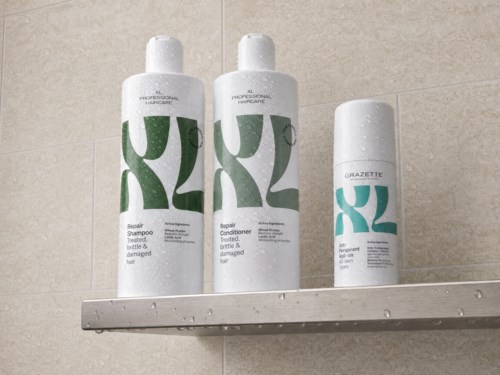 Två vita flaskor med hårvårdsprodukter och en sprayflaska på ett badrumsskenk. Etiketterna visar gröna och blå design.