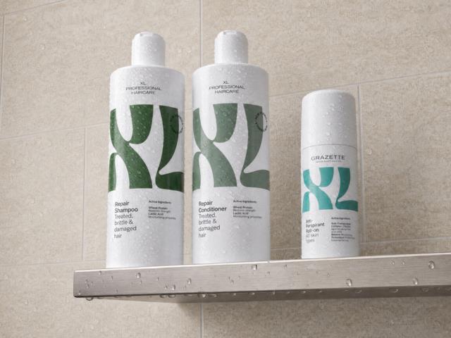 Två vita flaskor med hårvårdsprodukter och en sprayflaska på ett badrumsskenk. Etiketterna visar gröna och blå design.