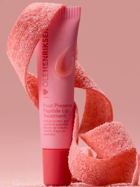 Pink lippleie tube med peel-ingredienser, omgitt av pink peel-strimler på en rosa bakgrunn.