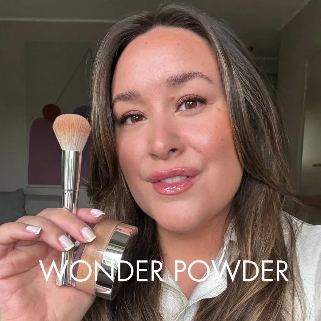 A woman holding a makeup brush near her face, with text saying "Wonder Powder."